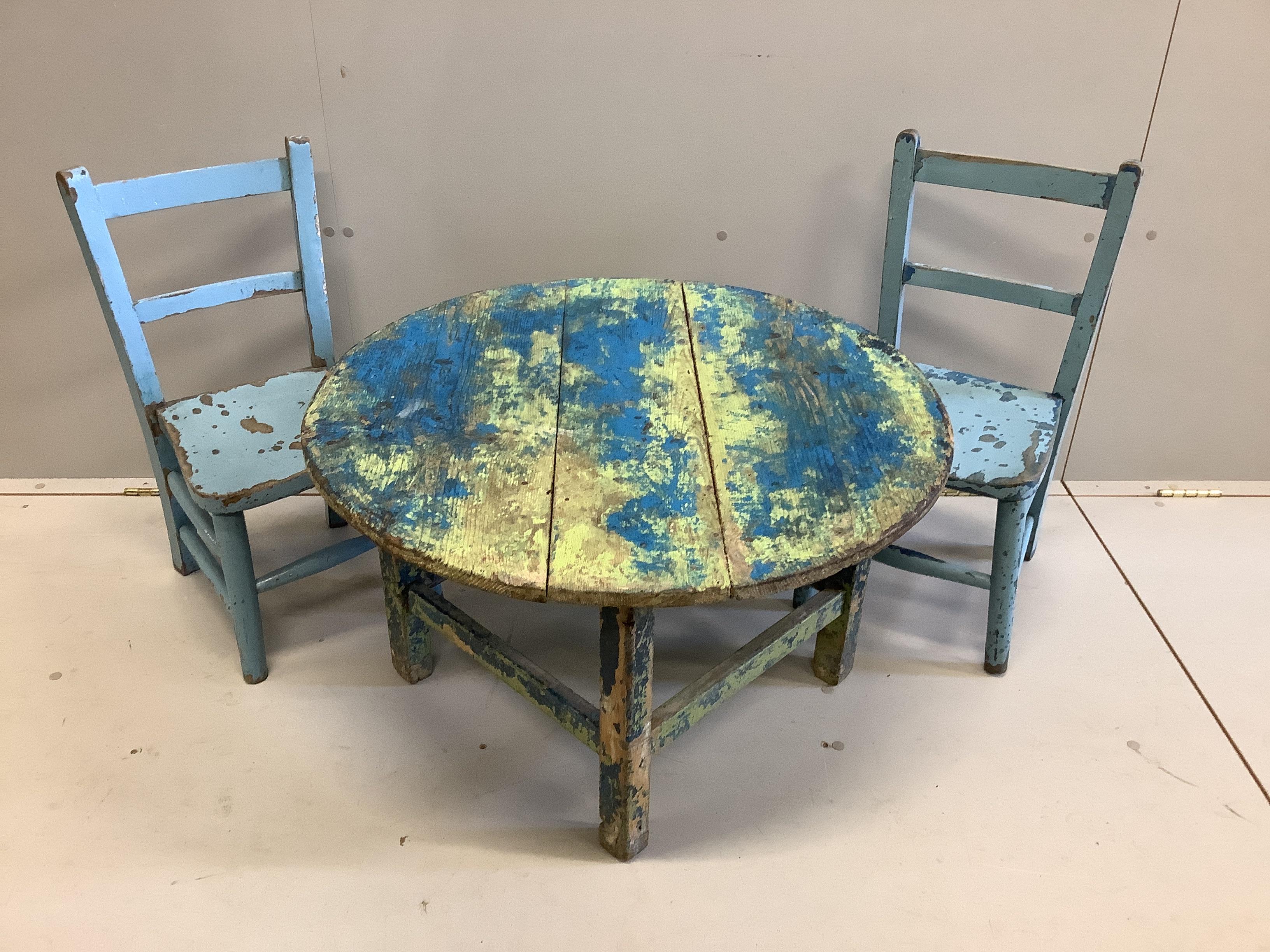 A circular painted pine low table, diameter 75cm together with two painted child's chairs